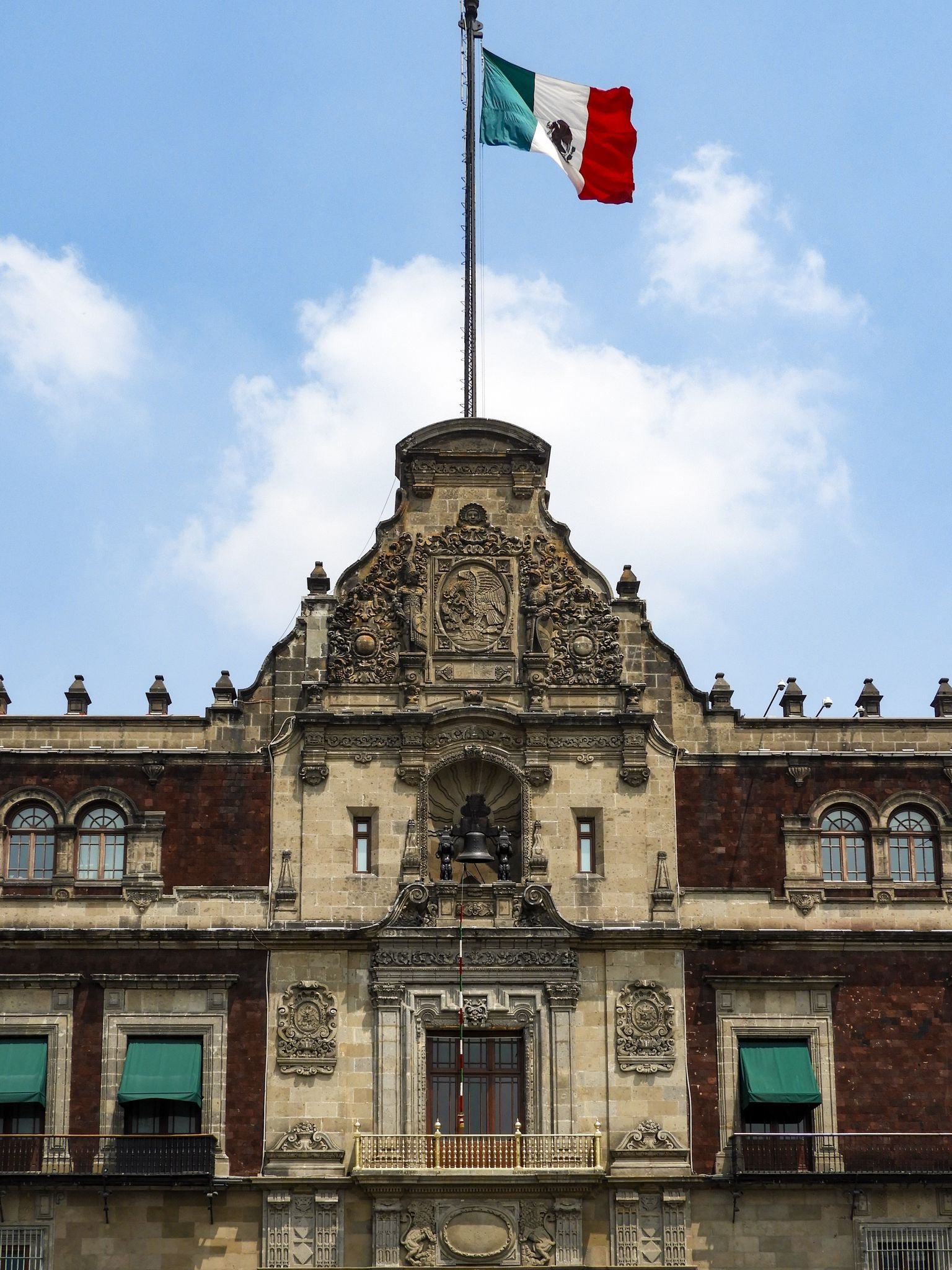 Ornate facade of a historic building in Mexico City with a Mexican flag waving above.